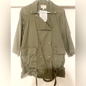 Green jacket with button closure and low belt buckle